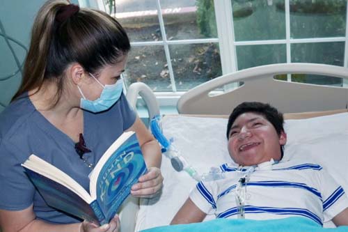 Staff reading to a boy who has a big smile